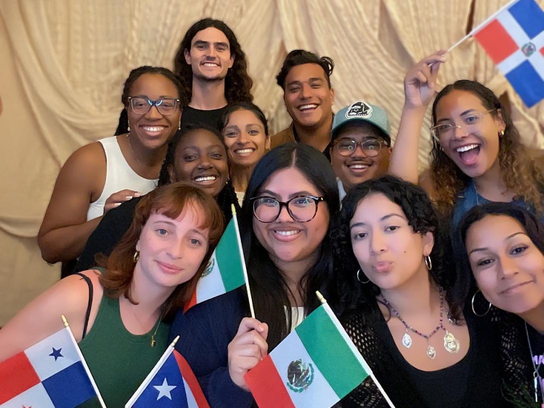 Photobooth image of a group of 11 LHM opening ceremony attendees with smiles and national flags